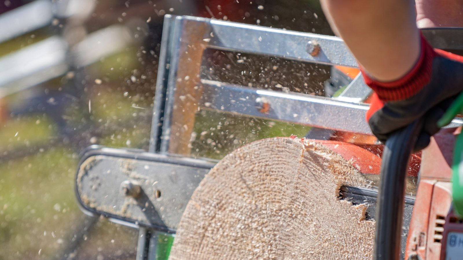 A chainsaw cutting through a log, sawdust in the air