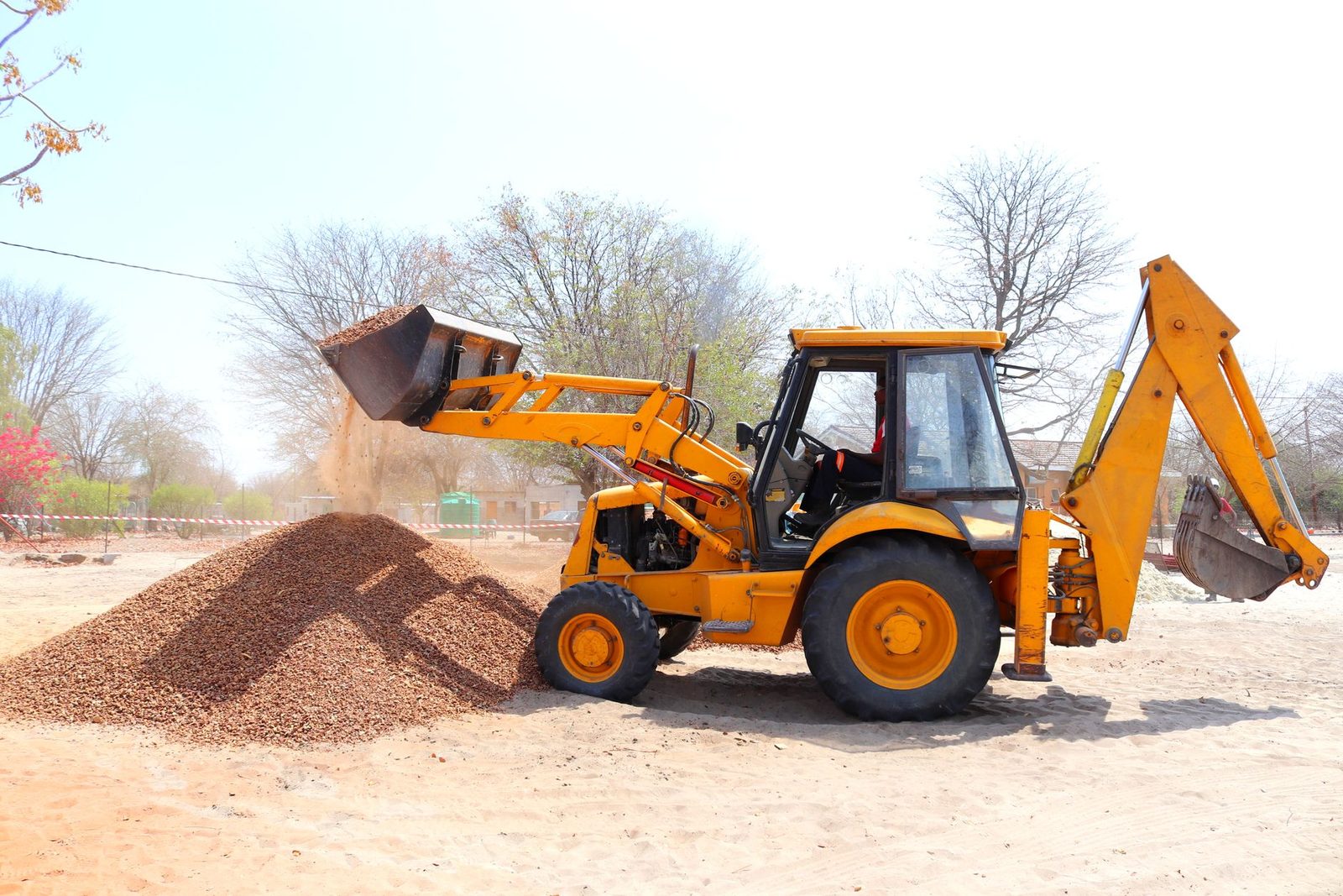 A small excavator working beside a gravel pile